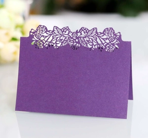 Macro view of laser-cut rose hollow pattern on purple pearlescent card for wedding decor
