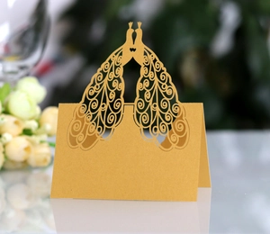 Detail of laser-cut peacock table card in gold pearlescent paper for weddings