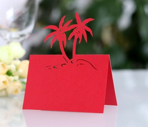 Detail of red laser-cut place card with palm tree design for beach wedding decor