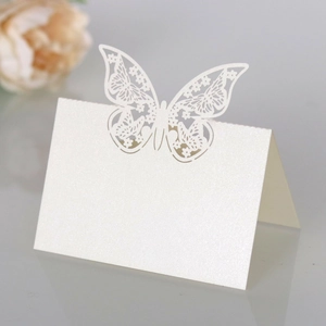 Macro detail of laser cut hollow butterfly place card in white pearlescent paper for weddings