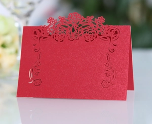 Close-up of red laser-cut place card with floral hollow pattern and pearlescent finish