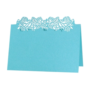 Macro view of laser-cut hollow rose pattern on light blue place card for wedding table