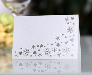 Close-up of white pearlescent table card featuring laser-cut butterfly heart patterns