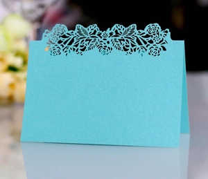 Detail of laser-cut rose patterns on light blue pearlescent wedding place cards