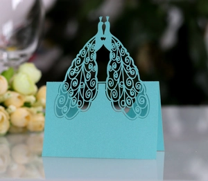 Close-up of sky blue laser-cut wedding place card featuring intricate peacock design
