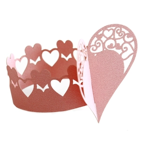 Macro shot of laser-cut heart paper napkin ring with pink pearlescent finish and scrolls