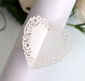 Macro shot of white laser-cut heart napkin ring with floral vine pattern