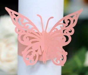 Pink laser-cut butterfly napkin ring with intricate scroll patterns for elegant table decor