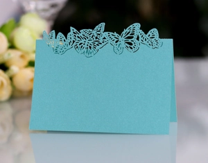 Detail of laser-cut butterfly place card in teal pearlescent paper for wedding table decor