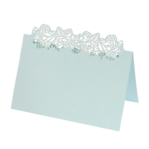 Detail of light blue laser-cut table card featuring an intricate rose and leaf pattern