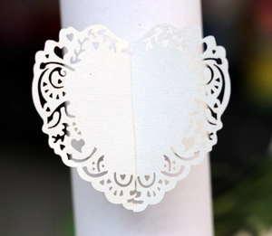 Detail of laser-cut heart pattern on white paper napkin ring for wedding decor