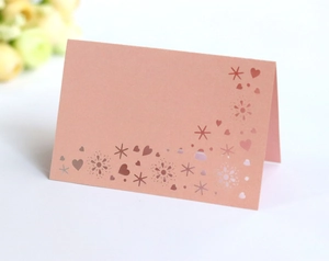 Detailed view of pink laser-cut heart and star patterns on pearlescent wedding place cards