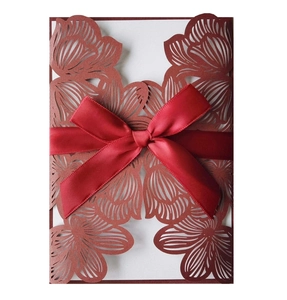 Detail of laser-cut dark red floral wedding invitation cover with silk ribbon bow