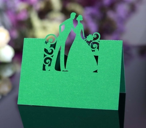 Laser-cut green wedding place card with bride and groom silhouette and floral patterns