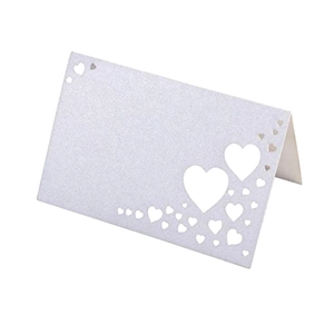 Detail of laser-cut heart pattern on pearlescent white wedding place cards for table settings