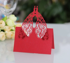 Macro shot of laser-cut red peacock table card with intricate hollowed scroll patterns