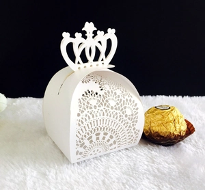 Macro shot of white laser-cut hollow candy box with crown top and lace pattern detail
