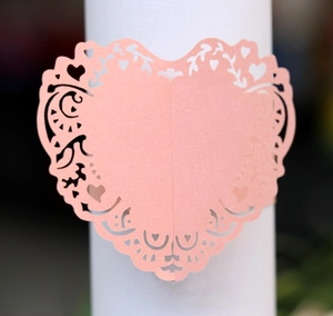 Macro detail of laser-cut pink heart napkin ring with delicate lace patterns and pearlescent finish