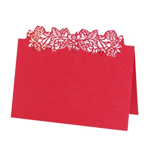 Detail of red laser-cut floral place card showing delicate hollow pattern and stand