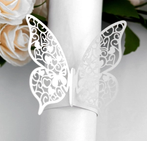 Close-up of laser-cut white butterfly paper napkin ring with intricate hollow floral patterns