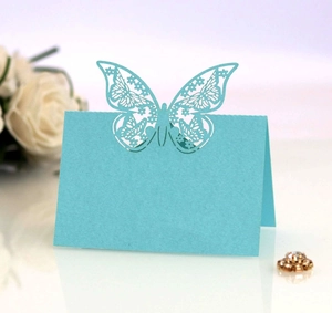 Macro shot of light blue laser-cut butterfly place card with intricate floral patterns