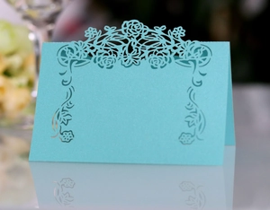 Detail of light blue laser-cut place card with elegant hollow rose and flower patterns