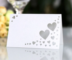 Detail of laser-cut heart place card on reflective surface for wedding decor