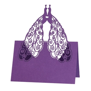Detail of laser-cut peacock wedding place cards in deep purple pearlescent paper