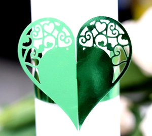 Detail of green metallic laser-cut heart napkin ring with intricate scrollwork patterns