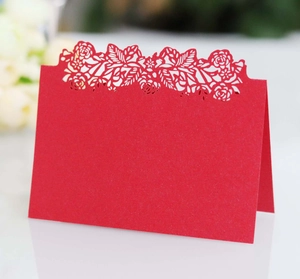 Detail of red laser cut floral place card with intricate rose pattern and pearlescent paper