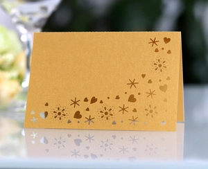 Detail of laser-cut heart patterns on elegant gold pearlescent folding place cards