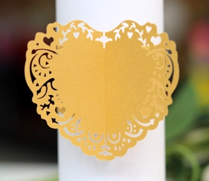 Macro detail of laser-cut heart paper napkin ring with yellow lace patterns for weddings