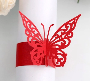 Macro detail of red laser-cut butterfly napkin ring with intricate floral patterns