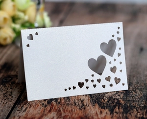 Macro detail of white pearlescent paper place card with hollow heart pattern