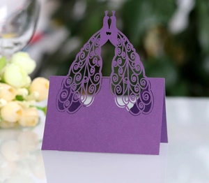 Close-up of laser-cut peacock place card in purple pearlescent paper for weddings