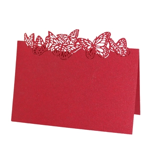 Macro detail of red laser-cut butterfly place cards with elegant hollow-out pattern