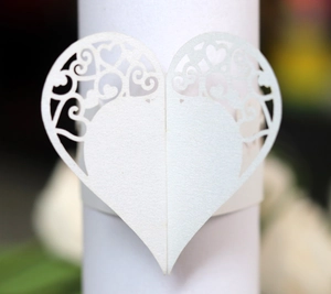 Macro detail of laser-cut white heart napkin ring with intricate vine patterns