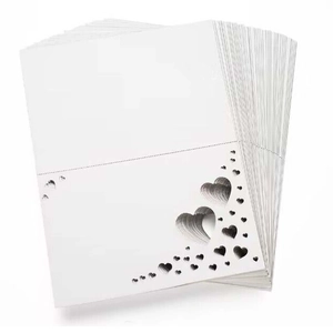 Detail of white paper place cards featuring elegant laser-cut hollow heart designs