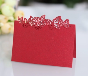 Macro detail of red laser-cut butterfly place card with elegant pearlescent finish