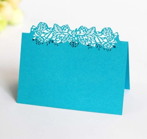 Detailed laser-cut floral hollow pattern on a turquoise folded wedding place card