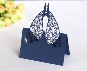 Detail of dark blue laser-cut table card featuring peacock and heart shaped pattern