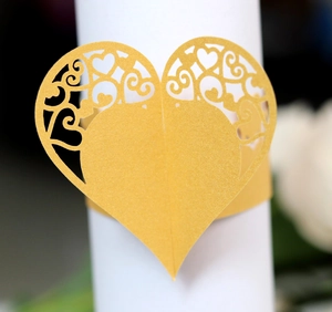 Macro detail of laser-cut heart napkin ring with intricate hollow floral patterns