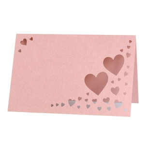 Macro shot of laser-cut heart details on shimmering pink pearlescent wedding place cards