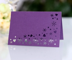 Macro detail of deep purple laser-cut place card with elegant heart and star patterns
