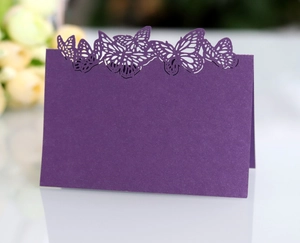 Close-up of laser-cut butterfly place cards in deep purple for wedding table decor