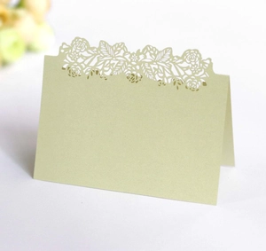 Close-up of sage green laser-cut floral wedding place card in an elegant folding design