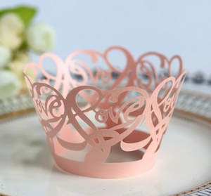 Detailed macro view of laser-cut pink pearlescent paper cupcake wrapper with Love pattern