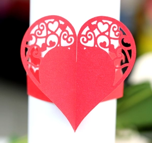 Macro detail of laser-cut red heart paper napkin ring with elegant hollowed lace pattern