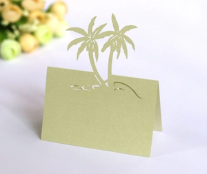 Detail of laser-cut palm tree place card in sage green paper for wedding table decor