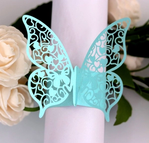 Detail of light blue laser-cut butterfly napkin ring with metallic luster on paper